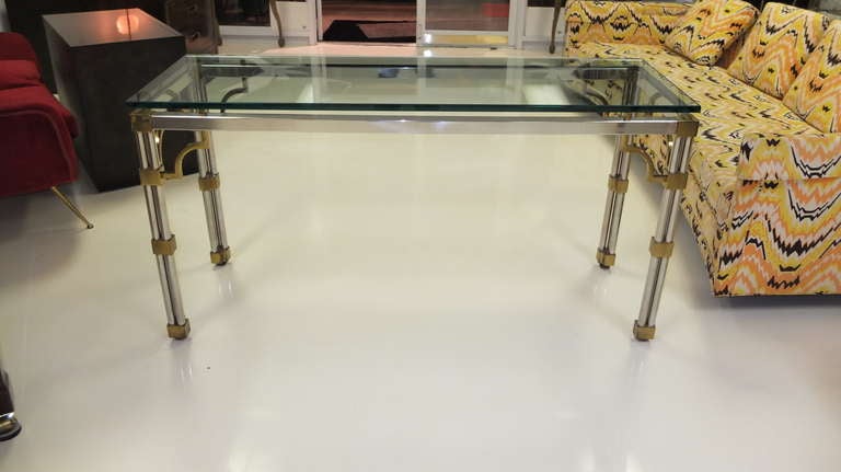 Tubular stainless steel with substantial brass embellishments and a hint of Asian modernist influence characterize this chic glass top console table.  Attributed to John Vesey.