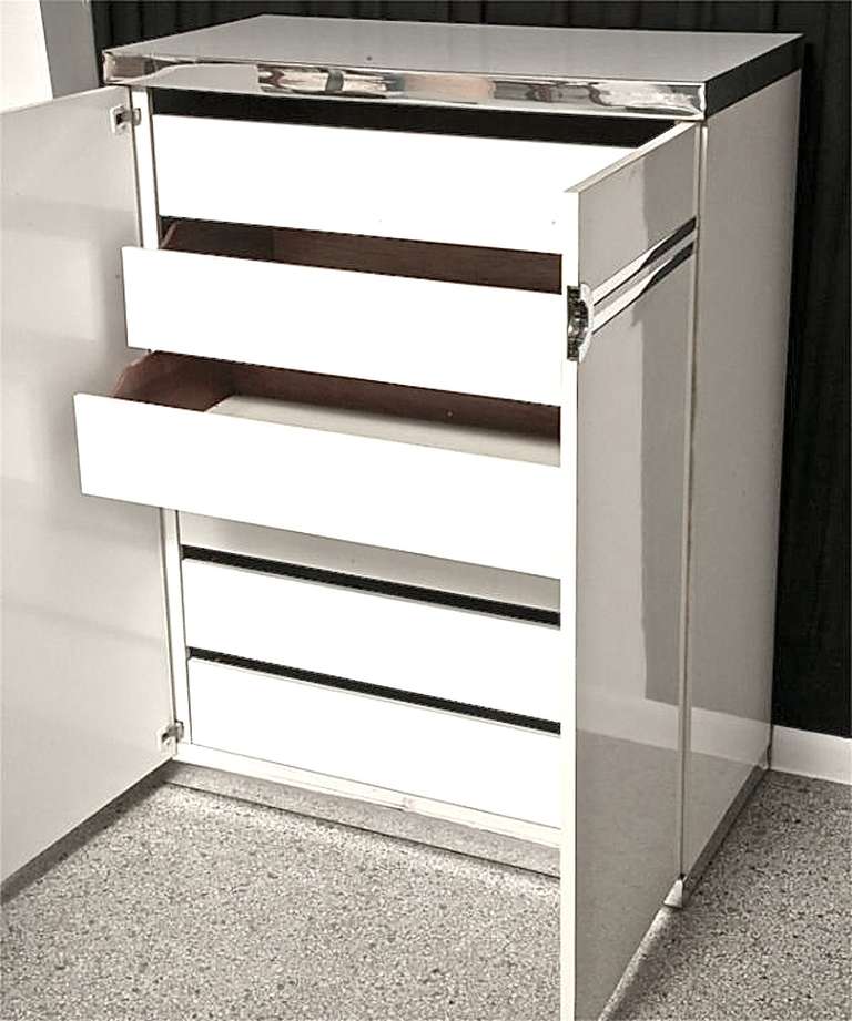 Abbiamo una coppia di cassettiere armadio alte Pierre Cardin con doppie ante che si aprono per rivelare 6 cassetti estraibili. Prodotto da Dilingham.  Laminato bianco con bande di alluminio lucidate a specchio come il cromo. Firma impressa dello