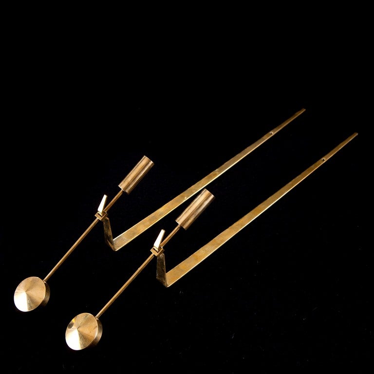 We have multiples of these Skultuna pendulum brass candle sconces by Pierre Forssell