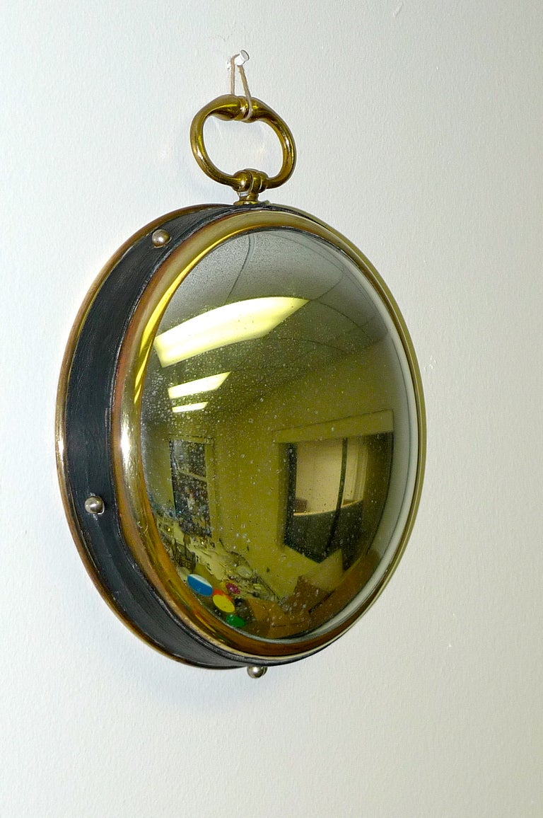 Charming wall mirror like a large pocket watch with a convex mirror with oxidized silver in a brass case with leatherette embellishment. In the style of Jacques Adnet.  11 inches high by 9 inches diameter.