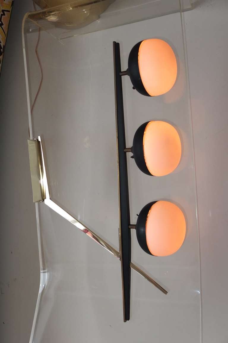 Extremely rare and unusual French 1950's sconce or ceiling fixture by Maison Arlus. Elbow form with heavy gauge solid brass tapering lines and dark wood with three lamp heads with bun shaped opaline half-globe shades.

Note we also have the