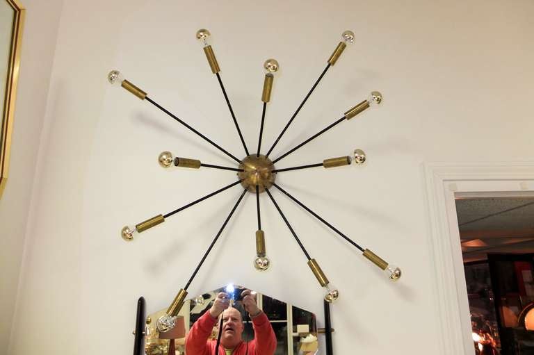 Splendid original 1950's Italian ceiling flush or wall mounted sputnik fixture produced by Stilnovo with 12 arms and made of solid brass.  

The central half sphere and solid brass cylinder socket cups are shown in their original natural brass