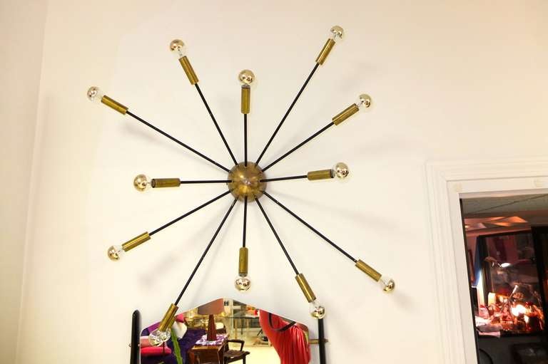 Splendid original 1950's Italian ceiling flush or wall mounted sputnik fixture produced by Stilnovo with 12 arms and made of solid brass.  

The central half sphere and solid brass cylinder socket cups are shown in their original natural brass