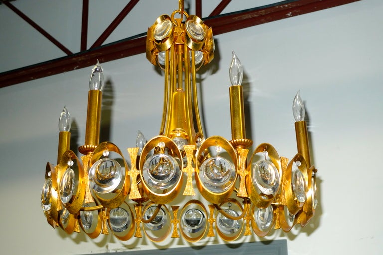 Elegant round chandelier made of textured gilt brass with concave/convex teardrop beveled crystal prisms within the outer rings of the chandelier structure.  Six brass candle stick lights.

Five inch diameter textured glass ceiling canopy for ease