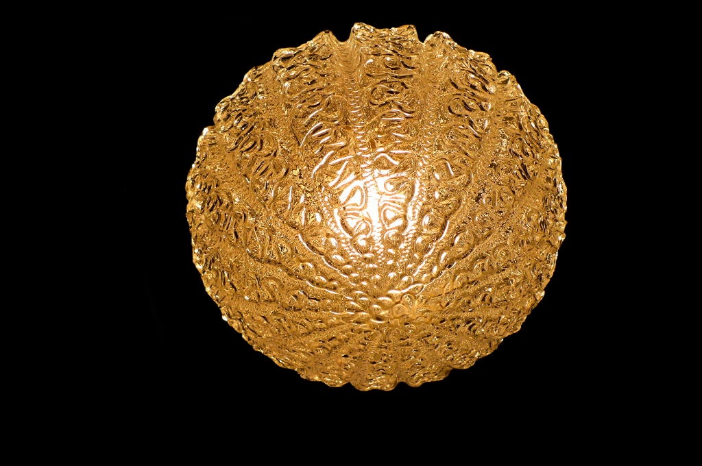 Molded glass pendant light fixture in the form of a sea urchin suspended by tubular steel rod and chrome canopy.