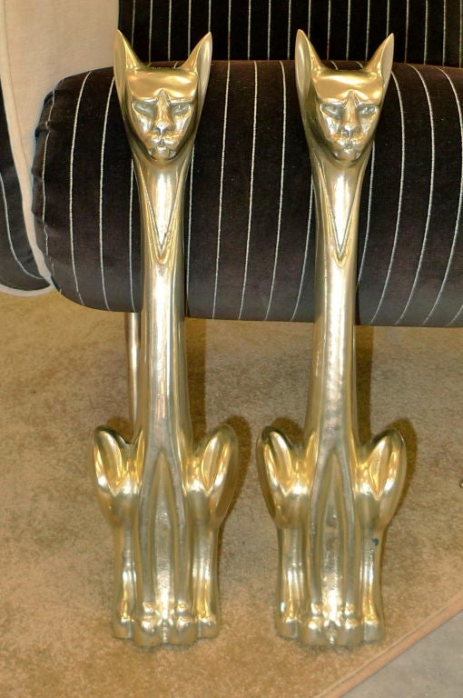 A pair of Modernist Brass Cat Andirons produced by the Tennessee Chrome Plating Company.<br />
<br />
Presently these do not have the cast iron log holders (easily found) so they can be used as door stops or decorative floor accessories.