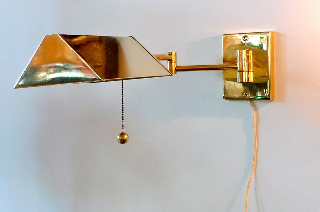 Stylish vintage pair of brass swing-arm pharmacy style wall lamps with brass triangular shade after Walter von Nessen and Koch & Lowy.  Comes with electrical plug-in cord but can be hard wired as well Brass ball pull chain.<br />
<br />
Price is