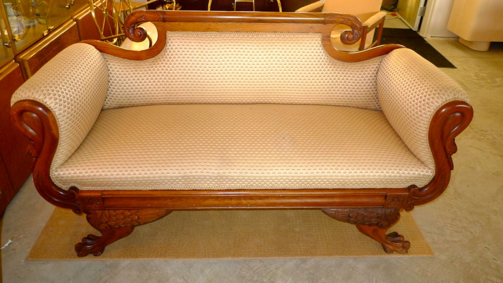 A fine and unusual example of American Empire small sofa (or love seat) with swan neck arms, winged paw feet and a richly carved and scrolled back rail.