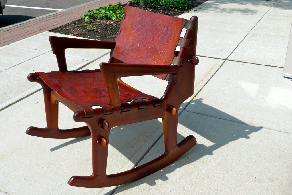 This rocker came to exist out of a 1960's Peace Corps initiative to aid local crafts people in Ecuador, with the assistance of Scandinavian designers, to produce and export furniture using local woods and hand tooled leather. The chair is held