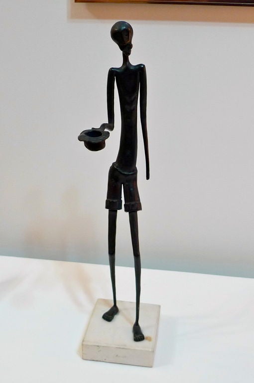 Iron sculpture on stone base of Giacometti-esque tall skinny man with open hat in outstretched hand. Surreal. Facial expression reminiscent of 'The Scream' by Edvard Munch.  Attached plastic card of the artist.