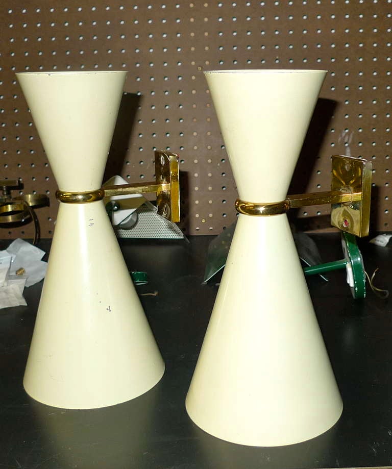 High quality pair of 1950's Italian wall sconces with brass mounts and enameled aluminum double cones.  The larger bottom cone having an Edison screw size bulb (60w max), the top a candelabra size bulb (25w max).  Rewired.  Original enamel.