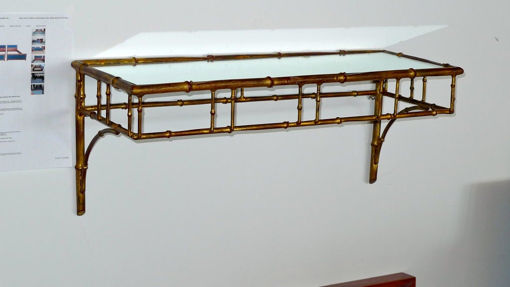 Hollywood Regency gilded iron faux bamboo wall shelf with mirror top.
