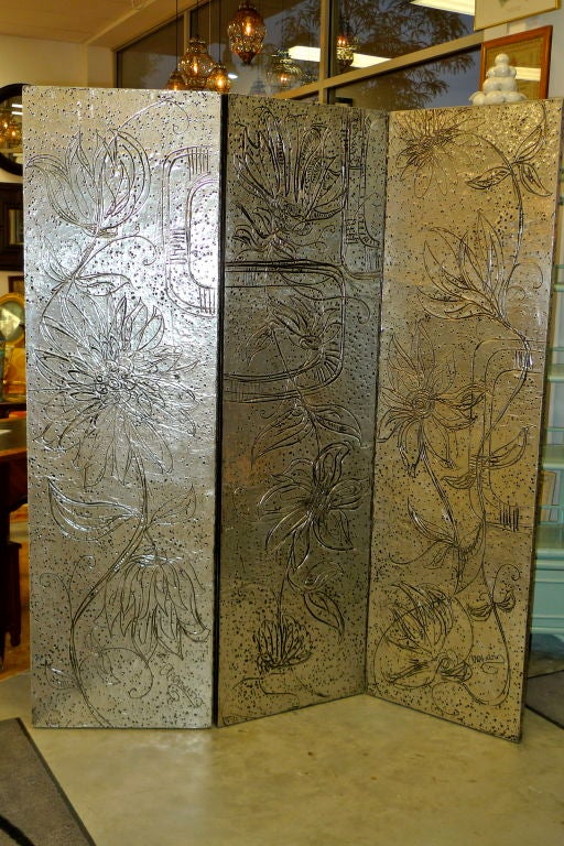Large three panel screen clad in hand etched sheet aluminum or tin with artist's fanciful floral designs. Each panel is signed 'Arenson' then the middle panel has an applied label from 'Arenson Studios, WPB, FLA'