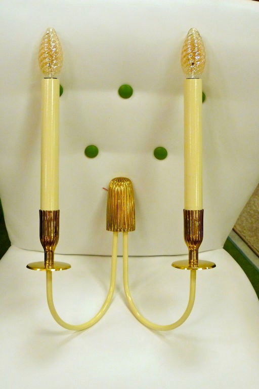 Pair of 1950's Italian wall sconces designed by Bruno Chiarini with long double candle holders extending from enameled iron arms and polished brass fittings.  Simple and easy to mount.  