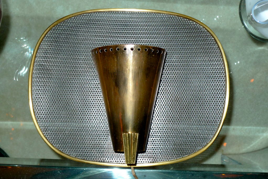 Single applique light in the manner of Mathieu Mategot and Jacques Biny with single bronze half cone mounded to enameled perforated steel in brass banded frame. Attributed to Kobis et Lorence.<br />
<br />
Companion sconce also available with