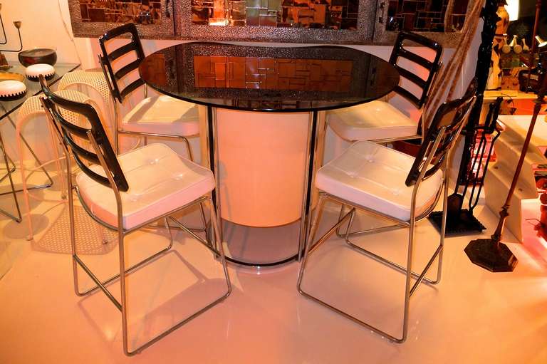 Vintage 1970's standing bar and four high chair bar stools by Chromcraft.

Bar is chromed steel square bar barrel form frame and white laminate cylindrical cabinet with an oval black smoked glass top.

Bar stool chairs are chromed steel rod with