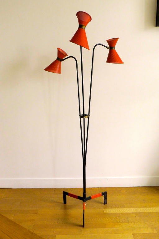 Seltene französische dreibeinige und dreiflammige Stehlampe von Lunel aus den 1950er Jahren in der Art von Mathieu Matégot.
Dreibeinige Struktur, drei dicke Arme aus schwarzem Eisen, drei gelenkige Diabolo-Schirme aus rot emailliertem, perforiertem