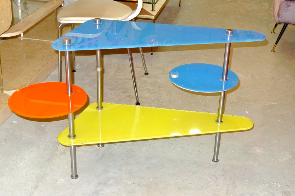 Whimsical multi-color and multi-tier etagere table or display stand produced in France circa 1950's by Etalages Dekora, Nantes.  Yellow and blue wedge shaped glass shelves are stationary while the orange and blue glass 12 inch diameter disks can