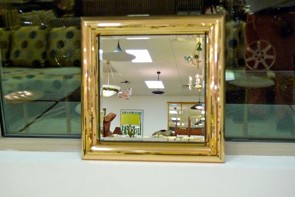 Square wall mirror in round-edged frame which is clad with slim strips of gold acrylic mirror tile giving it a shimmering sparkly disco mirror ball effect.  <br />
<br />
John Gilmore was born in Long Beach, California and has been designing