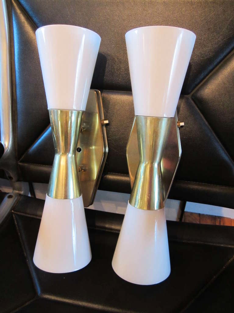 These long and elegant sconces have double cones which were inspired by the form of rocket boosters in the atomic age of the late 1950s.  Each cone can hold a 75 watt bulb, providing generous illumination. Diamond form back plate.