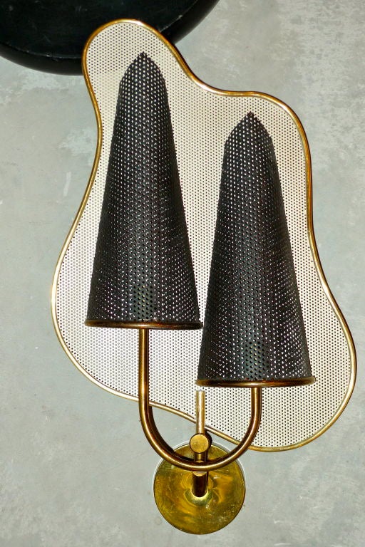 Rare applique designed by Jacques Biny and produced by Kobis-Lorence, France. Modernist amorphous reflector in enameled perforated steel, framed in brass banding. Rewired.<br />
<br />
See companion sconce attributed to Biny.