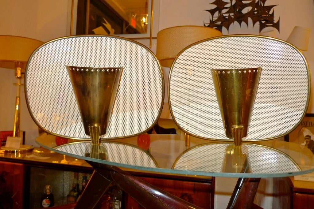 Pair of French Modernist wall sconces in the manner of Mathieu Mategot and Jacques Biny with single brass half-cone mounted to ivory enameled perforated steel in brass banded frame. Attributed to Kobis et Lorence.