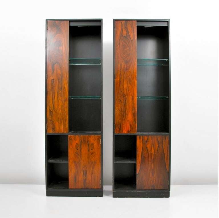 Pair of tall open display cases or shelving and storage units by Harvey Probber.  Ebonized oak and rosewood doors.  Open glass shelves are illuminated from above. Could easily function as bookshelves especially for larger books.