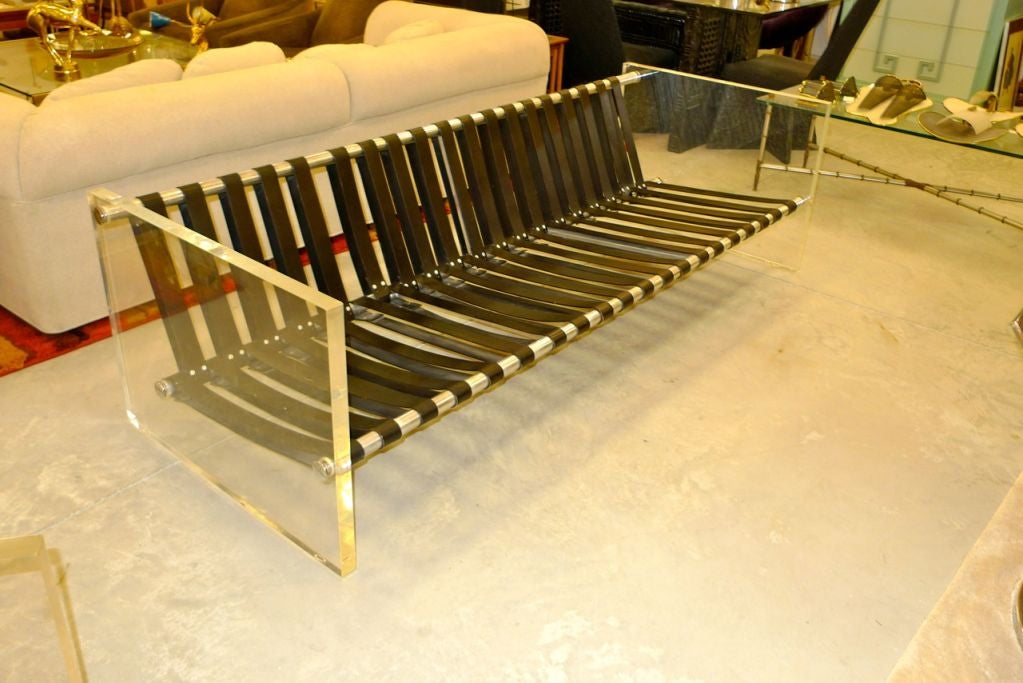 Ultra chic and uber quality sofa (and matching chair, separately) built with three industrial polished aluminum rods belted with black leather straps and ended with 1-1/2 inch thick slabs of clear Lucite.  We have chosen to present this without