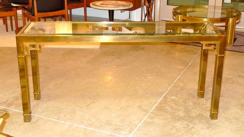 Patinated brass console table ib slim rectangular form with inset 1/2 inch thick beveled glass top, brass ferrules and brass Greek key corner brackets. Designed by William Doezema (1917 - 2009) for Mastercraft, Grand Rapids, the Company he founded