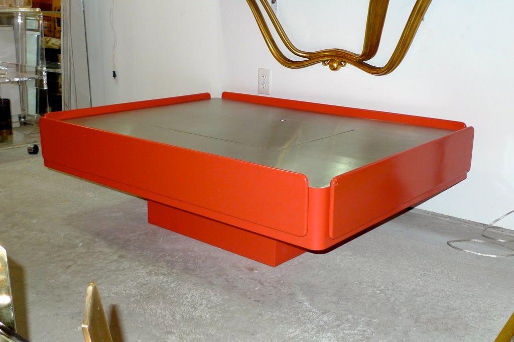 Vico Magistretti designed Caori coffee table produced by Gavina, Italy. Brushed aluminum top and coral tinted orange satin lacquered base.  The table has multiple storage areas: two drop down sides, two end drawers and top 
