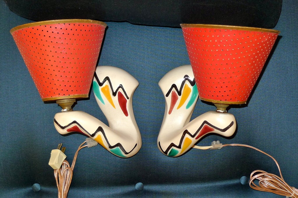 Tres jolie pair of whimsical French 1950's ceramic wall lights in colorfully painted matte off-white glaze in abstract form of a pair of arms holding torches with vintage French perforated paper uno ring shades