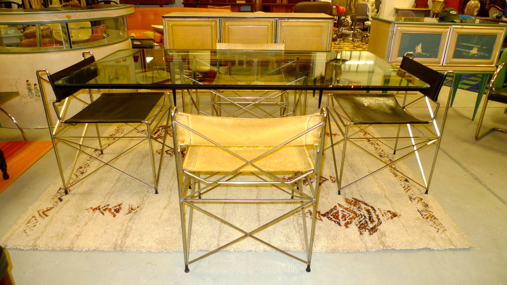 Table à manger minimaliste, sculpturale et dépouillée et quatre chaises de la collection Pace.  Des tiges et des plats en acier chromé s'entrecroisent dans une élégante formation architecturale en forme de cadre en x, sont soudés ensemble et forment