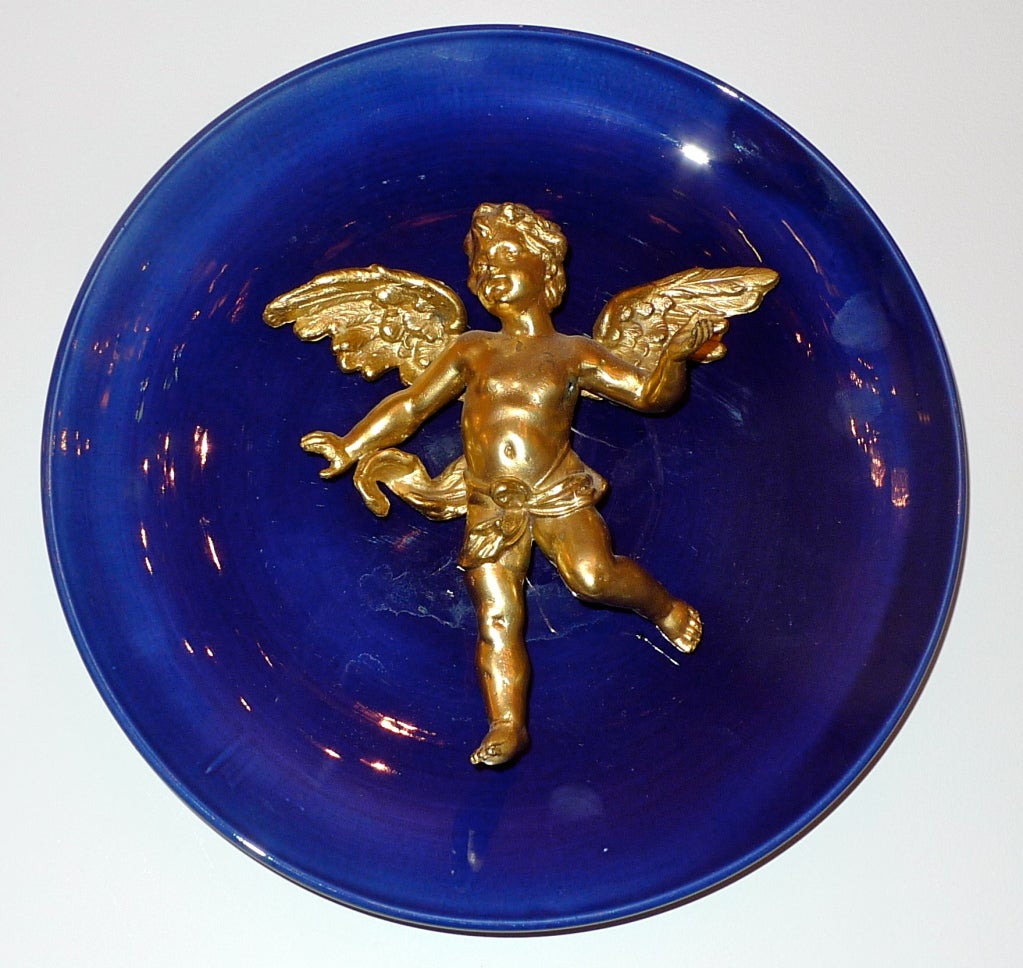 Ormolu Cherub mounted to cobalt faiance plate, the back fitted with a wire for wall hanging.