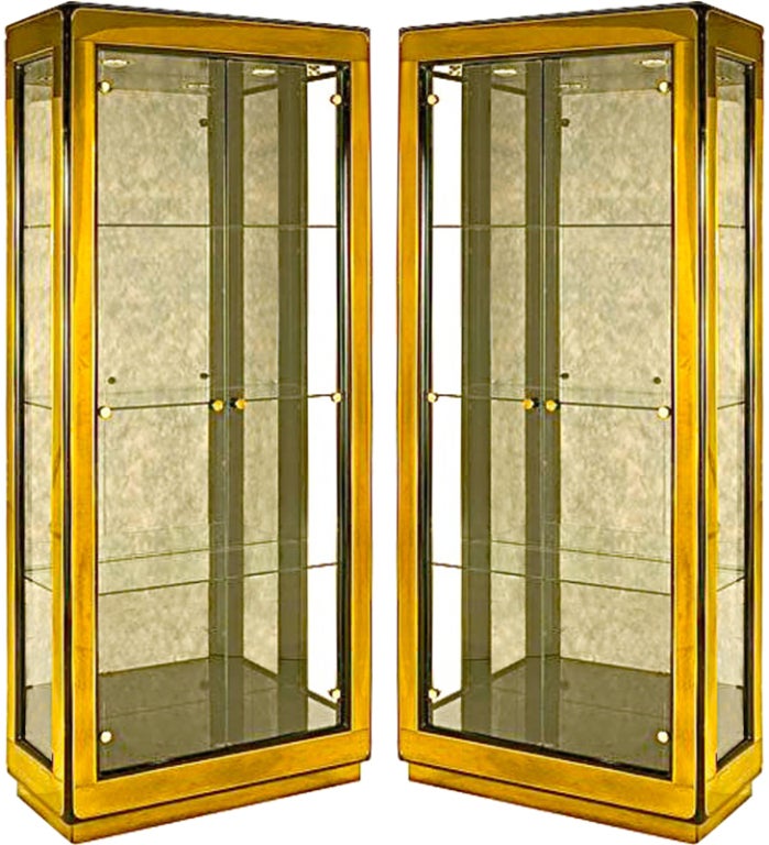 A pair of lacquered brass framed glass vitrines with beautiful smoke mirrored backs and glass doors and sides, glass shelves, recessed interior lights.  Labeled Mastercraft.
