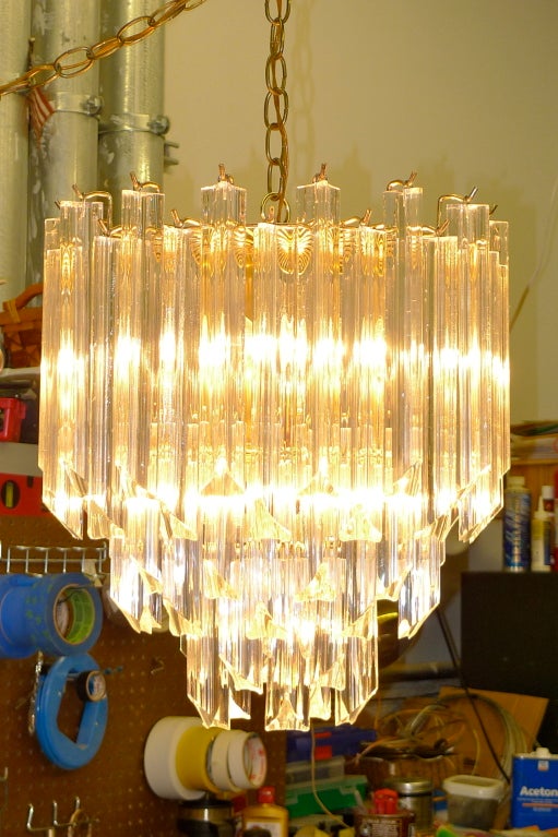 Produced in the 1960's by Tri-Arch in the style of Venini, glamorous chandelier coonsisting of a three tiered brass skeleton frame and triangular lucite prism crystals,