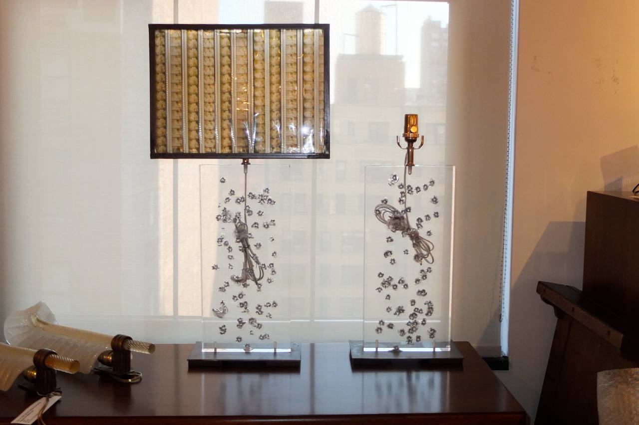 Pair of large scale table lamps made from one-inch thick Lucite slabs cut from an old acrylic security window salvaged from a bank undergoing renovations. Bases made from salvaged polished steel. 

Optional shade (only one) custom made from strips