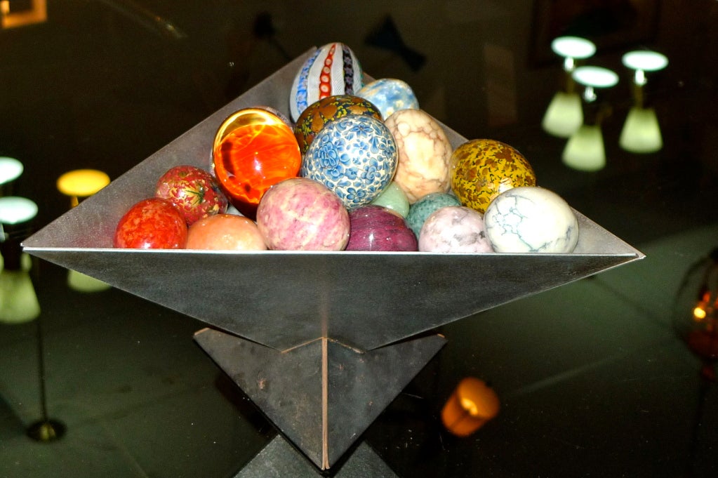 Sculptural art metal puzzle bowl made by Venice, CA artist Simon Maltby in which is displayed 29 decorative eggs in many forms including amber, jade, papier mache, enamel and Murano glass.  A wonderful centerpiece or chic display for an entry hall