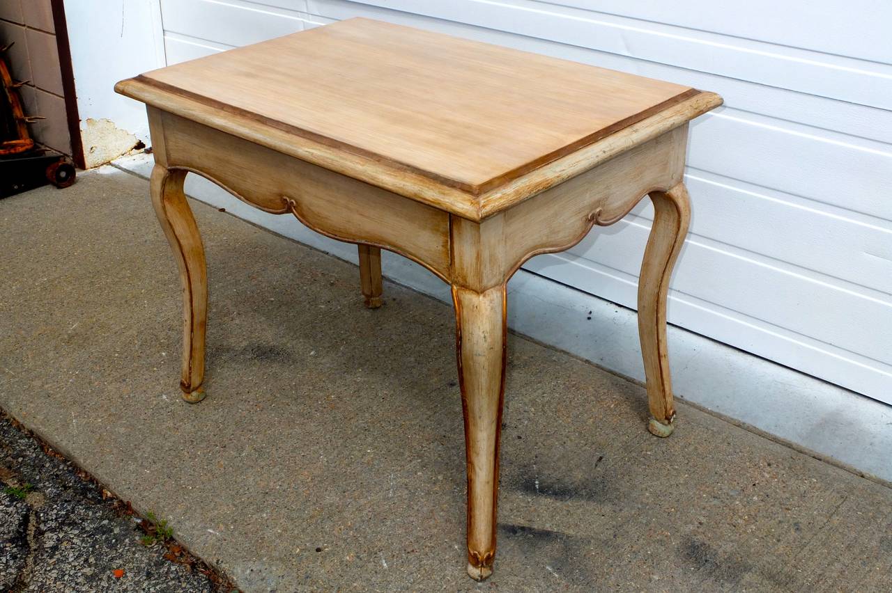 Italian 19th century side table which can also serve as a small writing desk. Molded rectangular top with scalloped apron one side of which is a pull-out drawer, and cabriole legs with interesting cloven hoof feet. Painted cream with gilding on legs