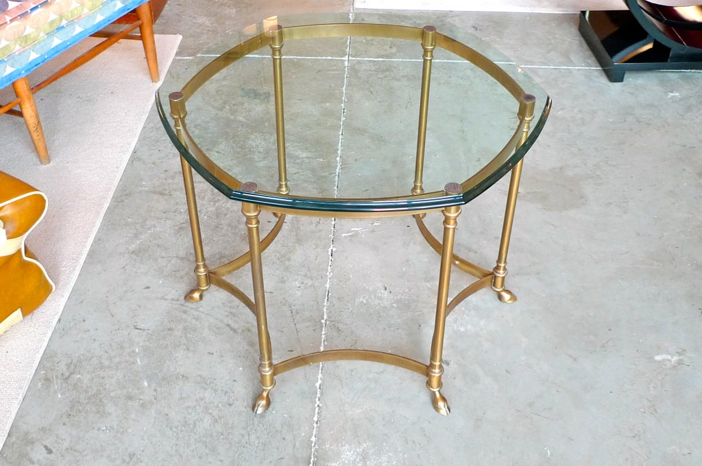 Neoclassical solid brass six sided table with six hoofed feet and signature LaBarge ogee beveled glass top. At 23 inches tall it is higher than most cocktail tables yet lower than a center table.