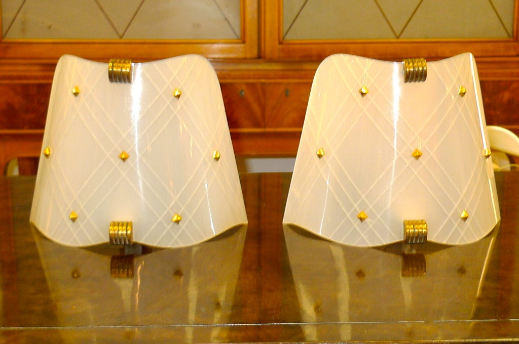 These have the most gorgeous shape and are in mint condition.  Small metal mount with single brass candelabra socket and gracefully formed shield reflector made of opaque plastic etched in Royere style criss-cross and embellished with brass studs