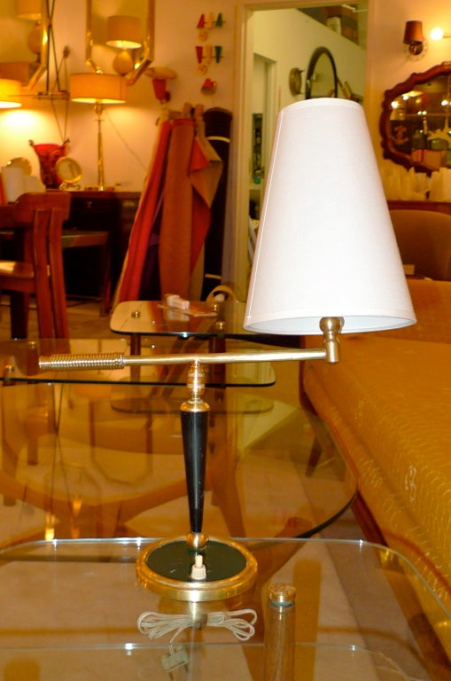 Handsomely crafted French 1950's table lamp with a an articulating arm on a machine milled swivel joint with brass coil wrapped handle on the arm and a conical white uno shade