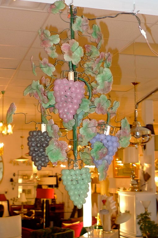 Our last two of these Italian chandeliers by Cesare Toso in the form of grape vines with handmade colored glass grapes and leaves on a scaffold of green enameled iron and wire tendrils. Five bunches of grapes illuminated by a single E12 candelabra