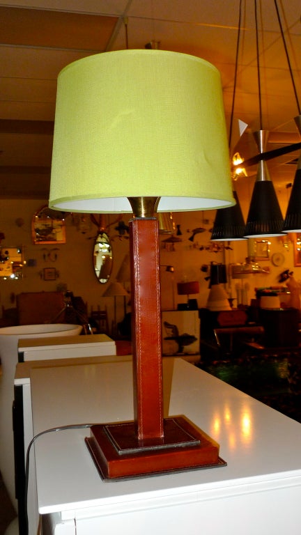 Französische quadratische Säulenlampe aus Leder mit Sattelnaht aus den 1950er Jahren, die Longchamps zugeschrieben wird und im Stil von Dupre-Lafon und Jacques Adnet gehalten ist.

Die Basis ist 7-1/2 Zoll quadratisch und die Höhe beträgt 18 Zoll
