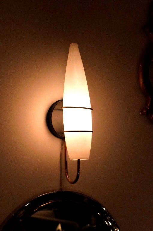 Applique simple italienne des années 1950 dans le style de Stilnovo.  Abat-jour en verre satiné de forme torpédo soutenu par deux anneaux en laiton avec une seule ampoule de bougie à l'intérieur.  Très attrayant.