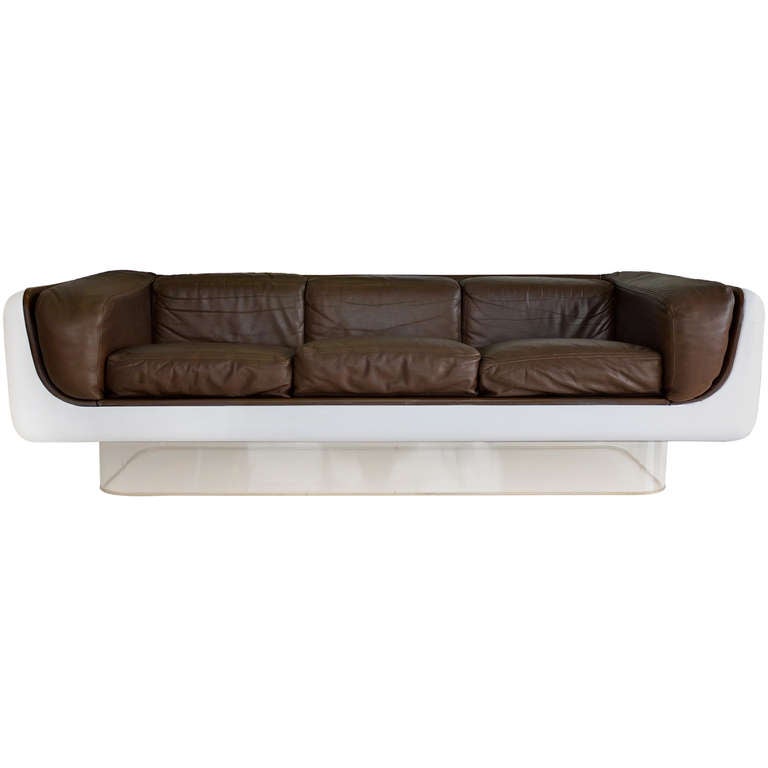Classic early 1970's sofa designed by Warren Platner for the ever innovative Steelcase with 2001 Space Odyssey stylings.  Painted white fiberglass shell appears to float on a lucite plinth.  Dark brown leather fitted cushions. An indisputable icon.
