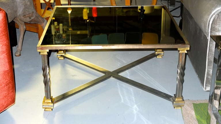 Large square coffee table in brass and twisted forged steel with X base cross stretcher and inset black glass top.