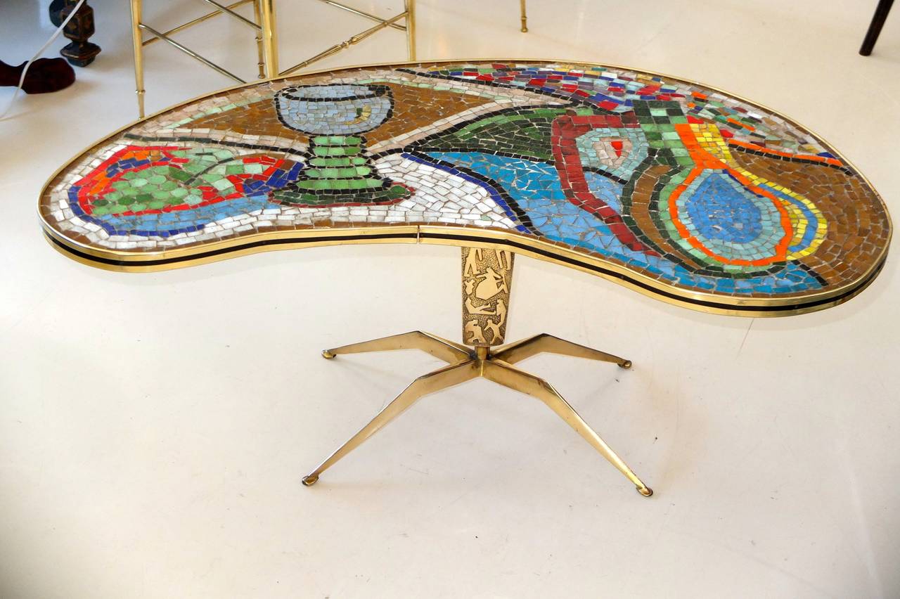 1950's Italian kidney shaped mosaic still life top on important cast brass base with four sculptural legs and a tapered single pedestal with modernist hieroglyph-like forms.  This same table base is sometimes seen with important glass tops from