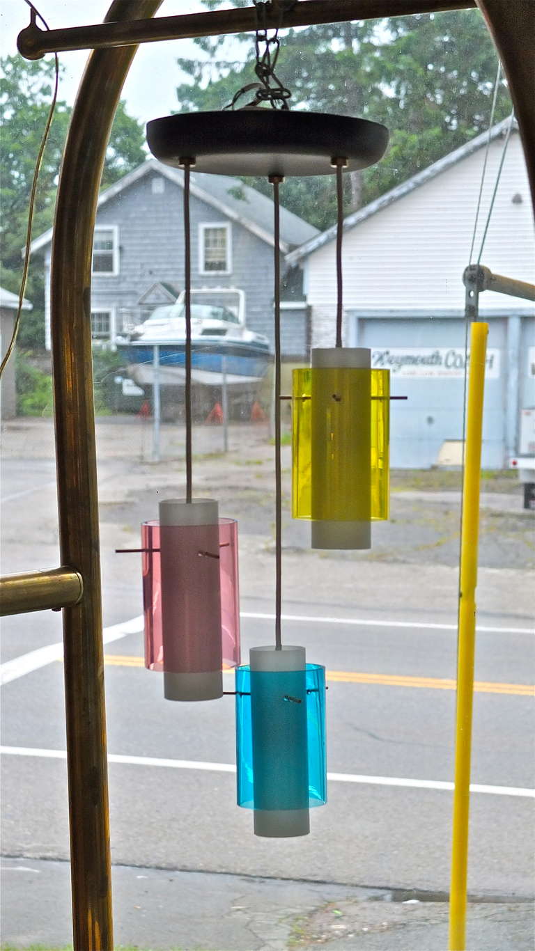 SATURDAY SALE


1950's Italian multi-colored glass cylinder pendants suspended from three white wire cords of staggered length from a single round flush mount ceiling canopy of black enameled aluminum.  The pendants are long slender opaque satin
