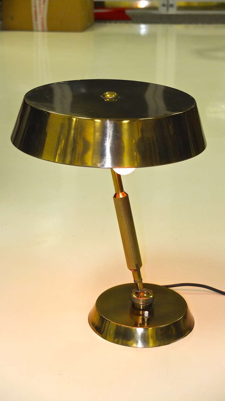 Solid brass Italian desk lamp with articulating circular deep dish shade and a giant swiveling ball joint where the stem meets the base. On off button switch on the base. Takes two standard size lightbulbs.