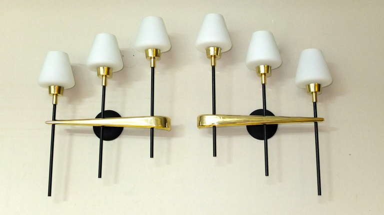 Pair of French 1950's wall mounted sconces from Maison Arlus each with three upright lights (ascending and descending like musical notes).  Each light has a single candelabra socket and a satin white cased glass conical shade.  Very heavy and